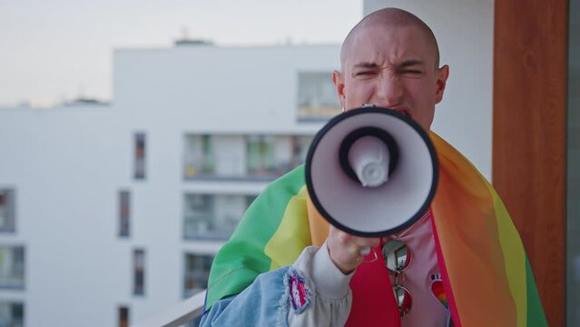 queer gay person screaming in ager and fighting for their rights with rainbow flag on shoulders. High quality 4k footage