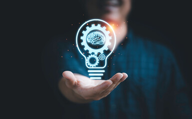 Businessman holding virtual lightbulb with mechanical gear and brain for creative thinking idea and innovation concept.