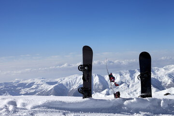 Three snowboards in snow near off-piste slope in sun day