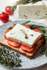 Appetizer sandwich with cherry tomato, cheese and italian herbs on a loaf of bread