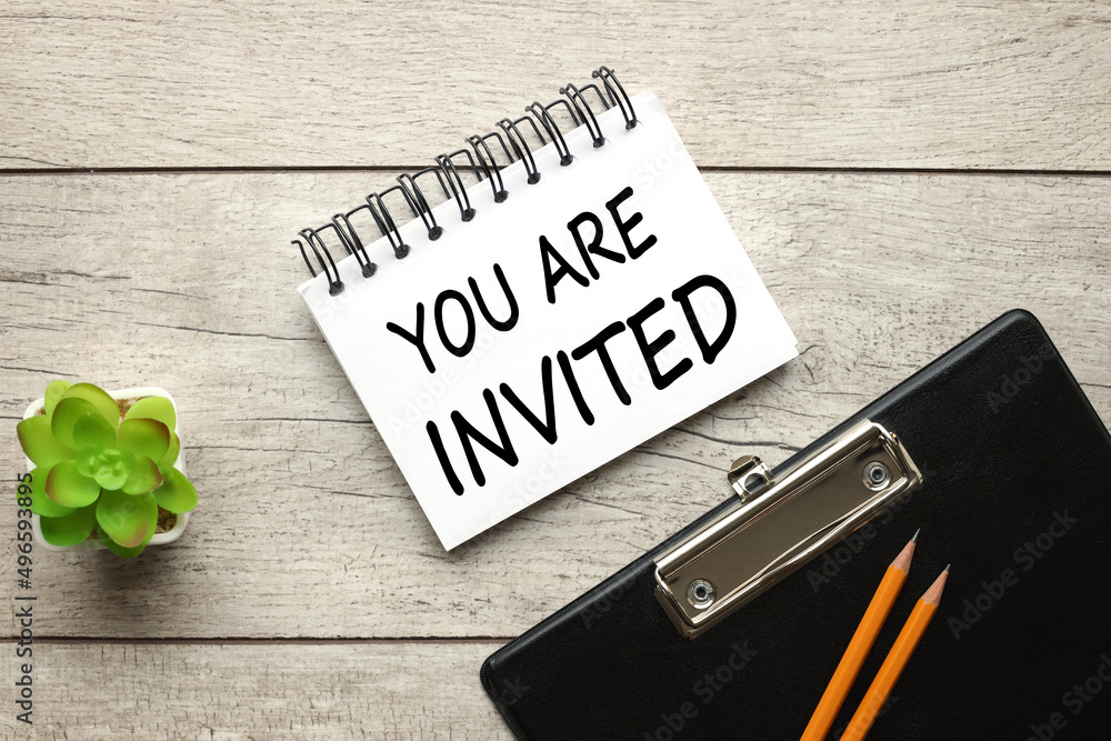 Aufkleber you are invited! text on an open notepad on a light table