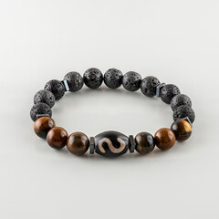 a bracelet made of round tiger eye stones and volcanic lava. Perfectly polished to a shine with glare reflection. white background.