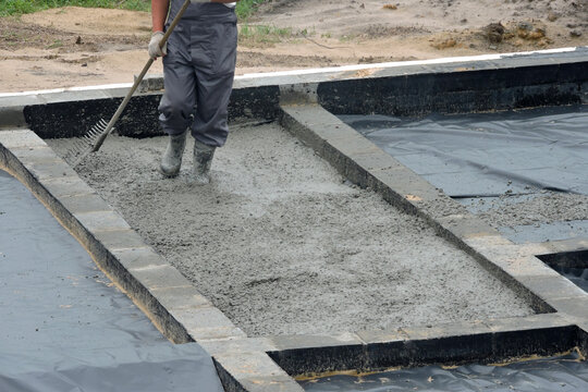 A builder levelling and spreading concrete with a rake