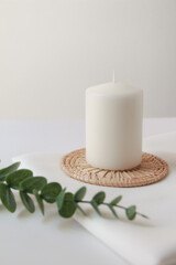 white candle with green eucalyptus on white background, modern and cozy  home