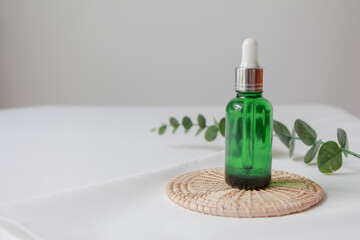 Dropper bottle serum on wood plate. Natural facial essential oil or serum packaging on white fabric background. Beauty product branding mock-up.  Cosmetic skincare concept. 
