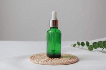 Dropper bottle serum on wood plate. Natural facial essential oil or serum packaging on white fabric background. Beauty product branding mock-up.  Cosmetic skincare concept. 