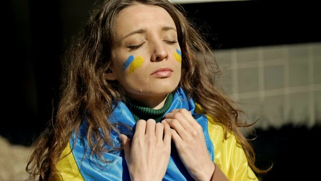 Portrait of a woman with a Ukrainian flag on his shoulders. Protest against the war in Ukraine and Russian aggression.