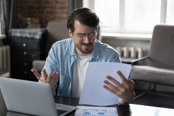 Annoyed frustrated entrepreneur man looking at paper report with bad news, getting problems,...