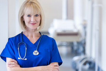 Smiling portrait of Caucasian female nurse wearing scrubs in hospital corridor