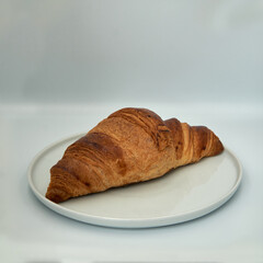 Croissant on a plate on isolated white background.