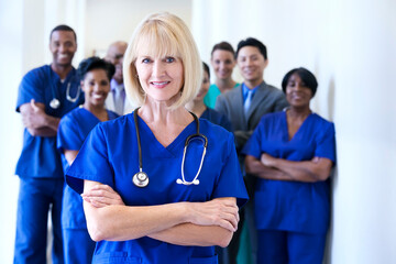 Smiling portrait female Caucasian nurse with multi ethnic team in medical centre
