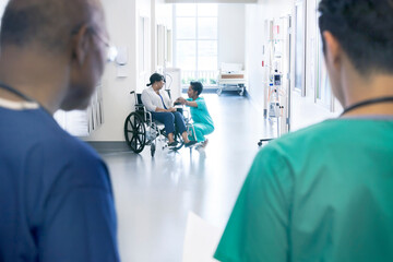 African American female patient in wheelchair with nurse in hospital corridor