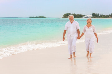 Happy mature Caucasian couple walking outdoors together on tropical beach