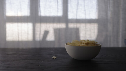 potato chips in white bowl on oak table