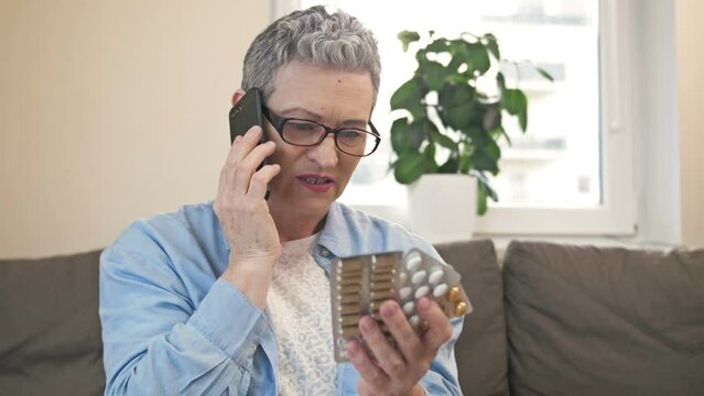 Mature woman consults with her doctor on the phone before taking the medicine she needs.