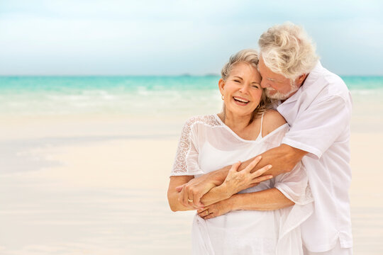 Senior Caucasian couple in casual white clothes happy together on tropical beach