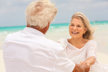 Attractive senior Caucasian couple living an island lifestyle dancing on beach