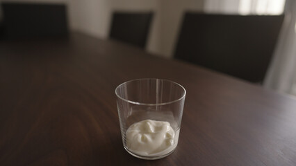 add yogut in tumbler glass on wood table