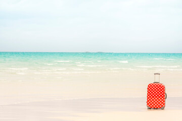 White tropical beach with a colourful red suitcase