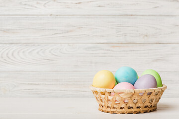 Multi colors Easter eggs in the woven basket on colored background . Pastel color Easter eggs. holiday concept with copy space