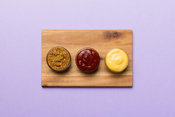 Different tasty sauces in bowls on plate on colored background. top view