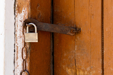 Padlock on an old brown wooden door with cracked paint. Close-up