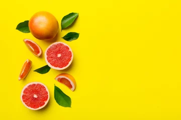 Foto op Plexiglas fresh Fruit grapefruit with Juicy grapefruit slices on colored background. Top view. Copy Space. creative summer concept. Half of citrus in minimal flat lay with copy space © sosiukin