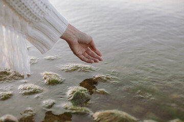 Picturesque frame of a beautiful female hand touches the water surface.