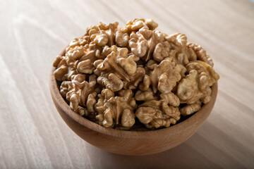 Bowl full of peeled walnuts on a wooden background,top view