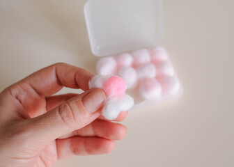 He holds wax pink earplugs in his hand. Wrapped in cotton