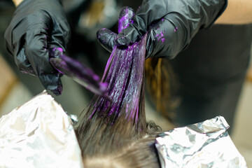 Dyeing a strand of hair purple. Hairdressing services in the salon