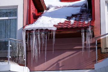 Large long icicles hang under the roof of the building