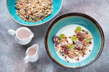 Bowl of greek yogurt served with granola and grapes, high angle view on a roseate metal background, horizontal shot
