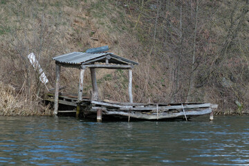 An old abandoned gazebo with a bridge for fishing on the river bank