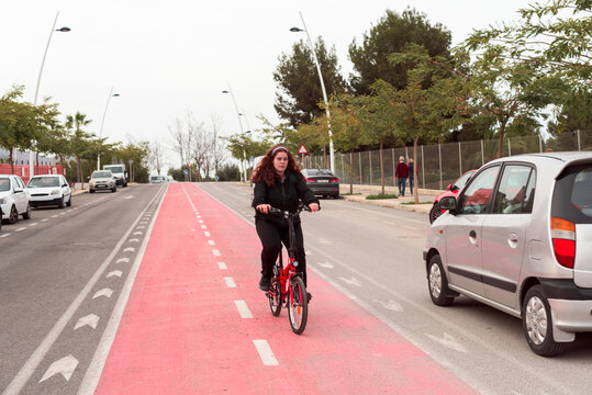 Front view of a young girl riding her bicycle in the bike lane in traffic.