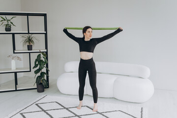Fitness woman exercising and stretching arms at home in the living room in sportswear. Female doing relaxing yoga and breathing exercises.