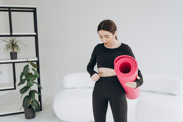 Young sport woman with mat at home celebrating. Concept sporty body