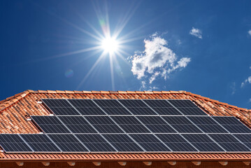 Roof with solar panels on blue sky with  sun rays, copy space © framarzo