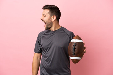 Young caucasian man playing rugby isolated on pink background laughing in lateral position - obrazy, fototapety, plakaty
