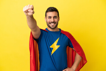Young handsome caucasian man isolated on yellow background in superhero costume with proud gesture © luismolinero