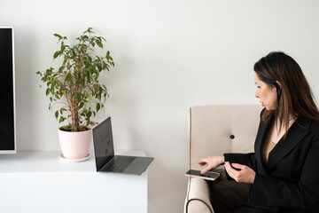 Business woman. A business woman works freelance on a laptop and uses a smartphone.