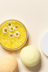 Bath salt sea and bath bomb with herbal extract of chamomile, sea salt crystals in jar, neutral beige spa background. Close up body care cosmetics, natural organic product, herbal medicine