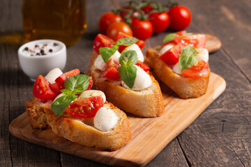 Italian tomato and cheese bruschetta. Tapas, antipasti with chopped vegetables, herbs and oil on grilled ciabatta and baguette bread.