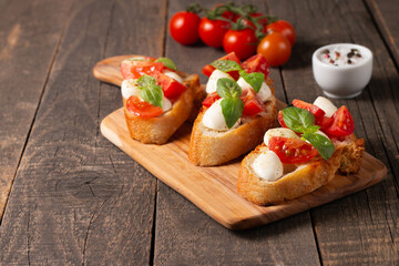 Italian tomato and cheese bruschetta. Tapas, antipasti with chopped vegetables, herbs and oil on grilled ciabatta and baguette bread.