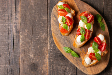 Italian tomato and cheese bruschetta. Tapas, antipasti with chopped vegetables, herbs and oil on grilled ciabatta and baguette bread.
