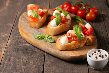 Italian tomato and cheese bruschetta. Tapas, antipasti with chopped vegetables, herbs and oil on grilled ciabatta and baguette bread.