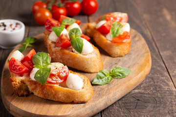 Fototapeta na wymiar Italian tomato and cheese bruschetta. Tapas, antipasti with chopped vegetables, herbs and oil on grilled ciabatta and baguette bread.