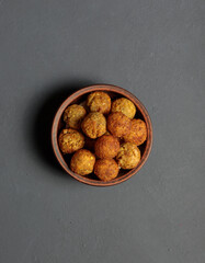a bowl with falafel or meatballs on a black background, top view.