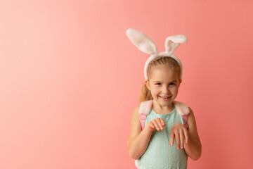 Obraz na płótnie Canvas Beautiful cute little girl in Easter bunny ears smiling on a pink background. Easter postcard