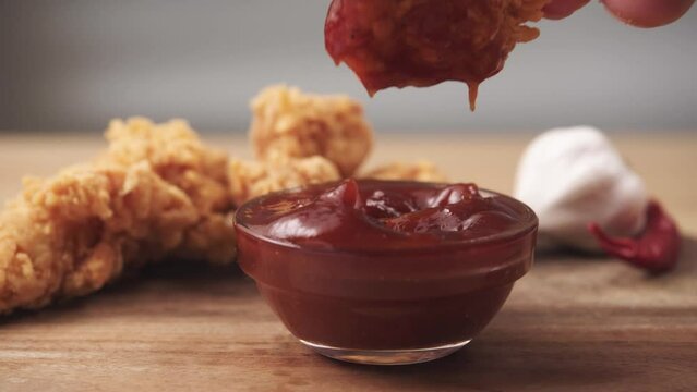 Dipping Chicken Wing into dip sauce on a table. Fast Food, Appetizer, Junk food and unhealthy eating concept